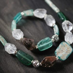 Close-up of a beautiful gemstone necklace and bracelet set on a dark wooden background.