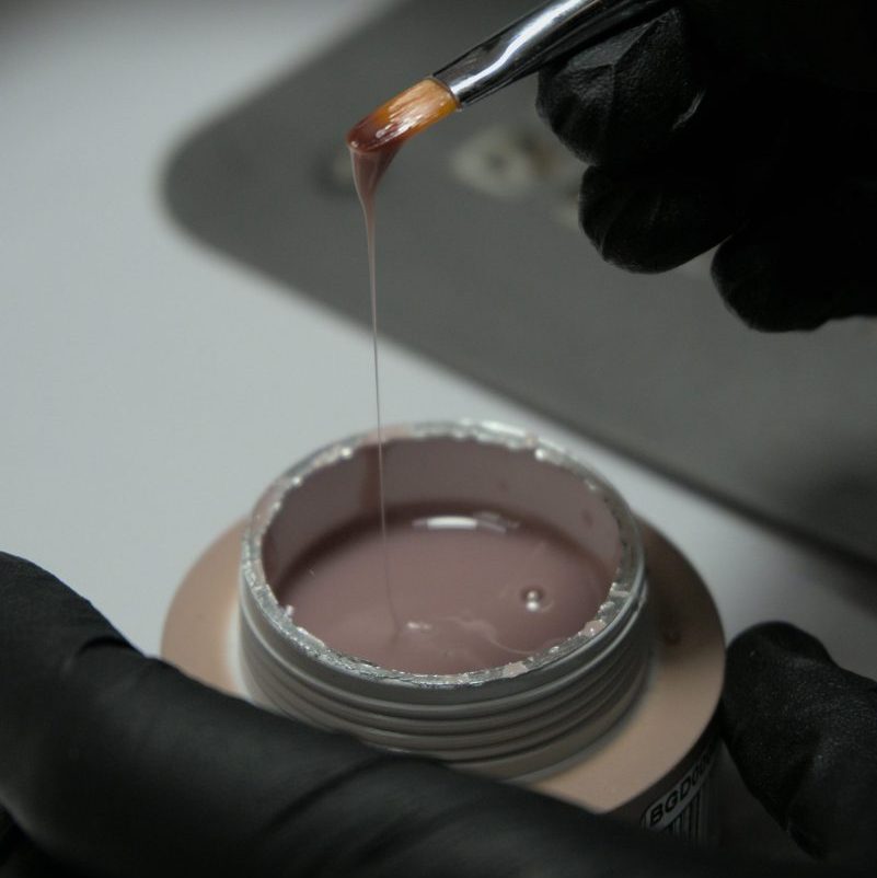 Detailed view of nail gel application with brush, showcasing beauty and care.