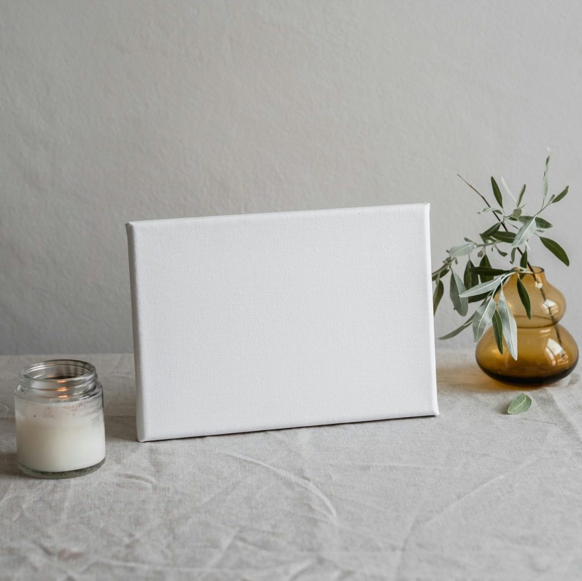Elegant minimalist canvas mockup on table with candle and vase, perfect for decor inspiration.