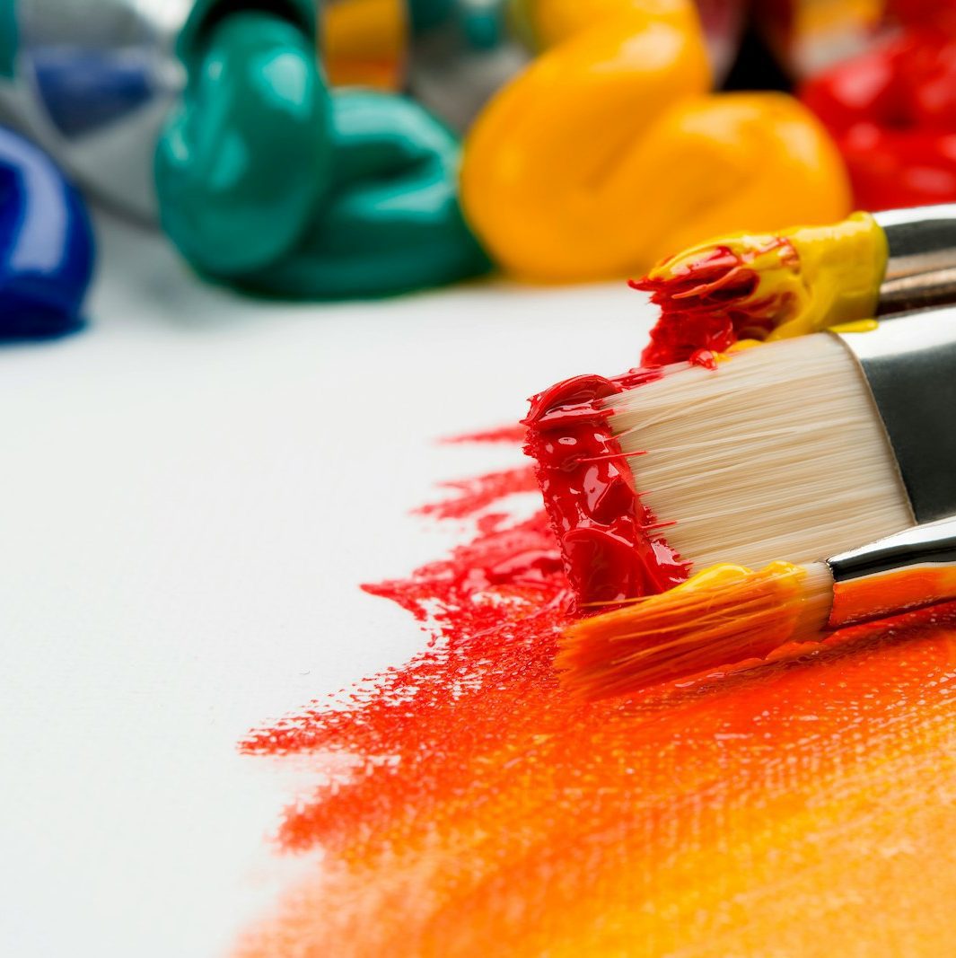 three silver paint brushes on white textile